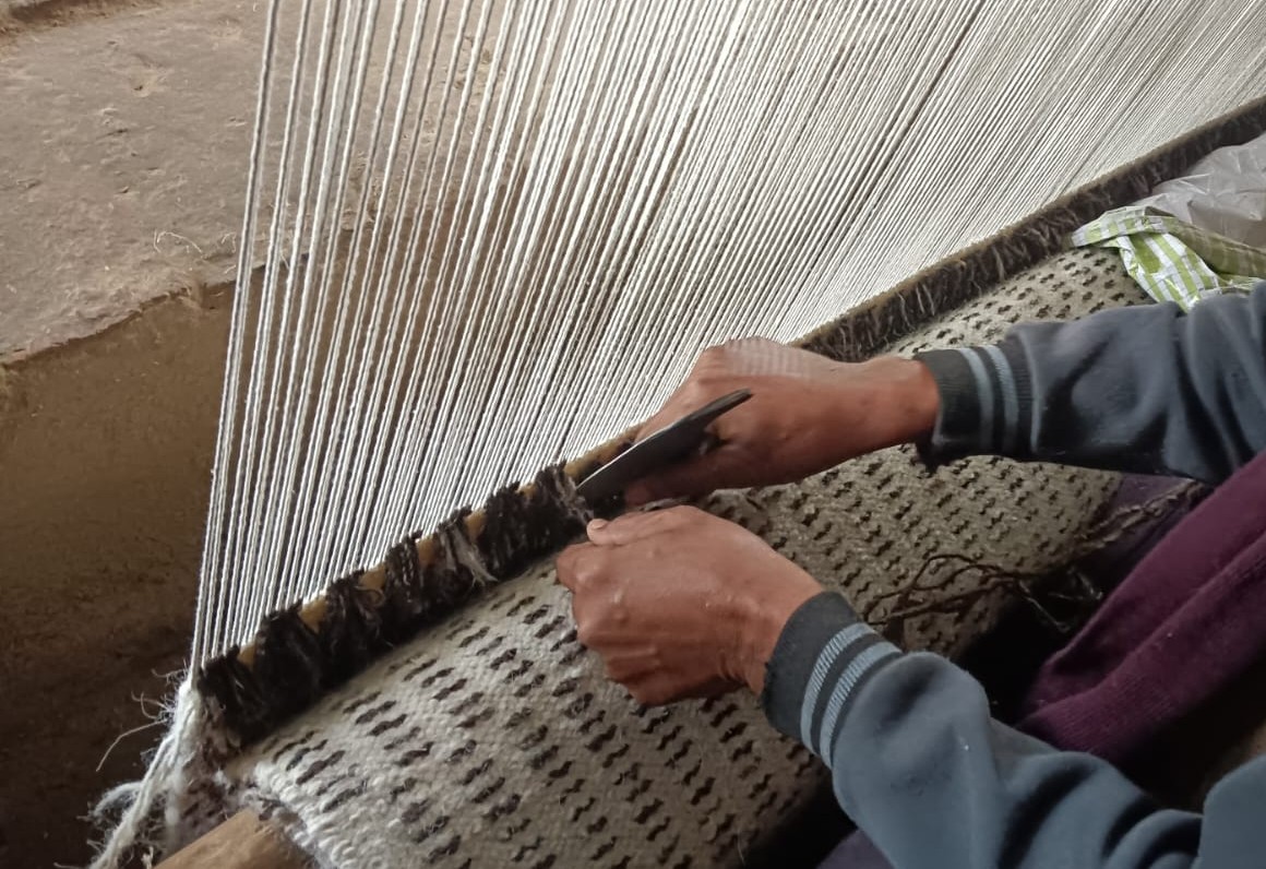 Artisan hand-knotting wool rug at Shaheen Rugs factory